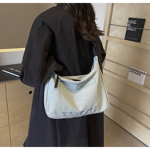 Dettaglio della borsa tote in tela grigia con tasca frontale a scatto in metallo e zip