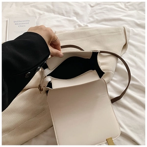 Close-up of off-white faux leather handbag interior with dark brown strap and gold buckle