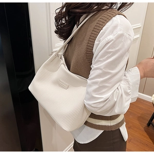 Close-up of beige pleated tote bag with fashion tag showing texture and stitching