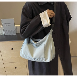 Dettaglio della borsa tote in nylon celeste con bottone a pressione su un cappotto nero