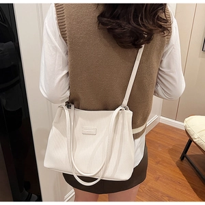 Rear view of a white corduroy tote bag with vertical stripes worn by a female model