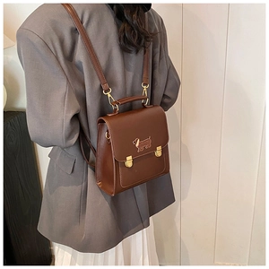Close-up of brown faux leather backpack featuring a gold dachshund logo and flap closure