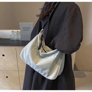 Dettaglio borsa tote in nylon celeste con tasca anteriore a patta e zip in tessuto scuro
