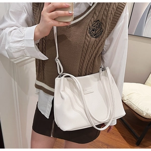 Vertical textured large tote bag with dual handles and slim shoulder strap shown on model