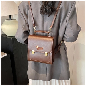 Brown leather backpack featuring a detailed dachshund embroidery and gold metal buckles