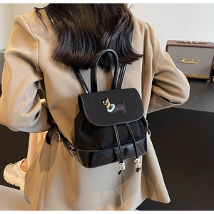 Details des Mini-Rucksacks aus schwarzem Canvas mit Stickerei und glänzendem Lackleder-Boden