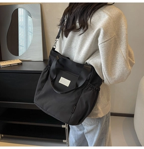 Detail of waterproof black nylon tote bag with side pleats and adjustable shoulder strap