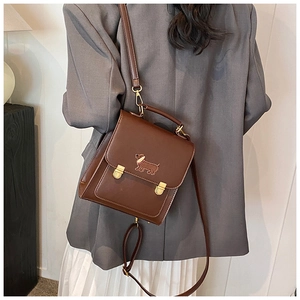 Detail of a dark brown PU leather backpack with a dog pattern and gold metal locks