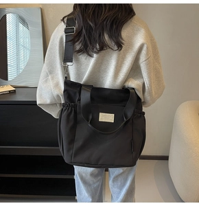 Detail of black waterproof nylon tote bag with adjustable strap and brand patch