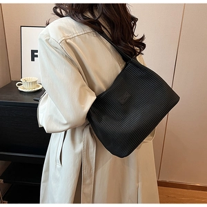 Detail showing high-quality black pleated texture and logo label on large tote shoulder bag