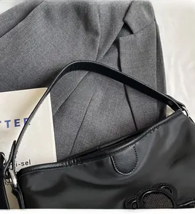 Gros plan du sac en nylon noir avec motif ours en paillettes et anses en cuir robuste