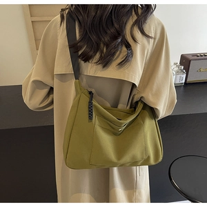 Dettaglio della borsa tote in nylon verde con tasca frontale e tracolla nera regolabile