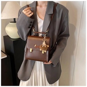 Detailed view of brown leather backpack with dog embroidery and plush charm accessory