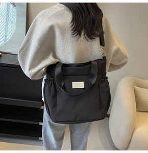 Rear view of a model wearing a black waterproof nylon tote bag with adjustable strap