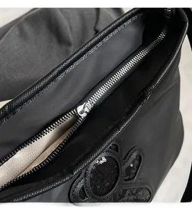 Détail de la fermeture éclair argentée avec logo sur sac de voyage noir à paillettes