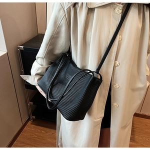 Detail shot of black pleated tote bag showing wrinkled texture and rectangle leather patch
