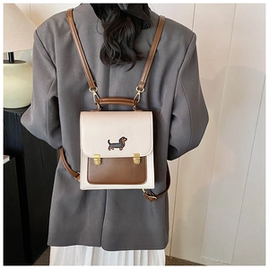 Detail of a chic cream and brown backpack with embroidery and gold clasp on model