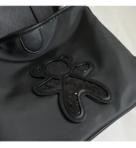 Gros plan d'un sac de voyage en nylon noir avec un patch ours en paillettes brillant