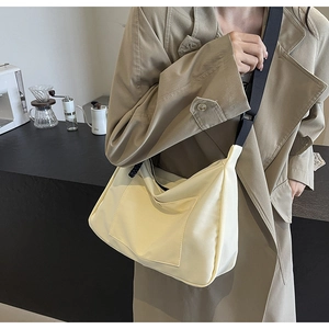 Dettaglio di una borsa a tracolla in nylon bianco crema con tracolla regolabile casual