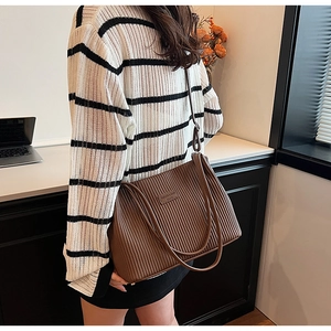 Detail of a brown pleated PU leather tote bag showing vertical quilted texture and handles