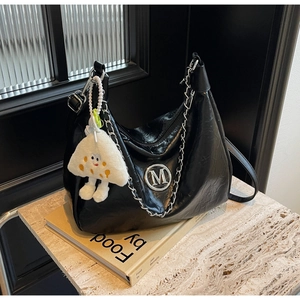 Close-up of black pleated PU leather shoulder bag with silver M logo and chain detail