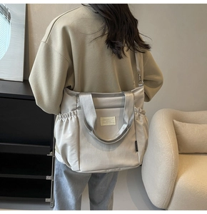 Close-up of lightweight nylon crossbody bag with side drawstring pockets and logo label