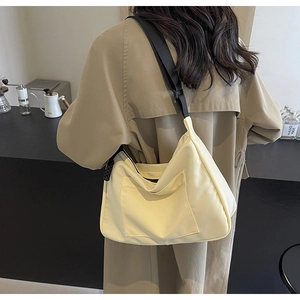Dettaglio della borsa tote minimalista in nylon beige con tracolla nera in un caffè