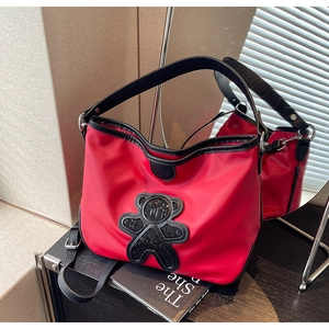 Détail du sac de voyage rouge avec ours en paillettes noires et bandoulière réglable