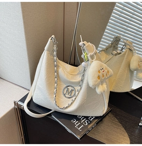 Detail of off-white ruched leather handbag with M logo, silver chain and plush charm