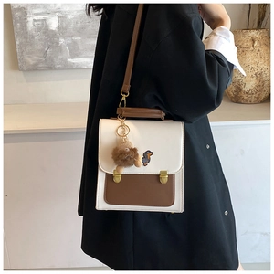 Close-up of retro color-block PU crossbody bag with dachshund patch and plush bear charm