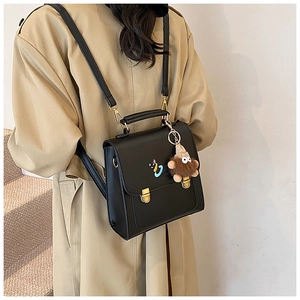Detail of black faux leather backpack with gold buckle and cute plush monster charm