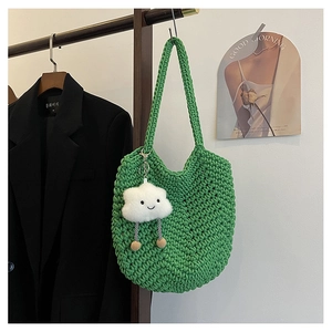 Detail of green woven shoulder bag with a cute white cloud plush charm on a hanger