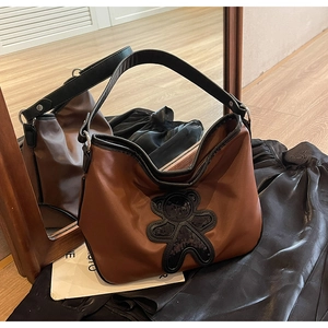 Détail du sac de voyage marron brillant avec ours en paillettes noires et large bandoulière