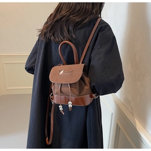 Detail eines braunen Vintage-Rucksacks mit Kontrastnähten und Hunde-Stickerei-Motiv