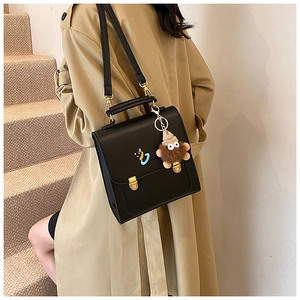 Close-up of black crossbody bag with gold hardware and a cute plush monster charm