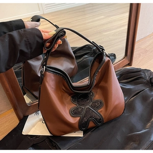 Gros plan du sac de voyage hobo marron avec ours en paillettes noires et doubles sangles