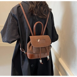 Detail eines braunen Vintage-Wildleder-Rucksacks mit dekorativer Dackel-Stickerei und Klappe