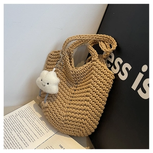 Detail of khaki woven tote bag with a plush white cloud charm on textured knit fabric