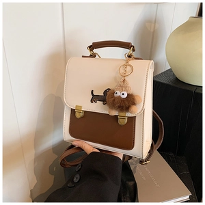 Close-up of cream and brown backpack with dachshund embroidery and plush charm