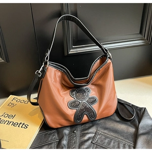 Détail du sac de voyage marron imperméable avec ours à paillettes et bandoulière noire
