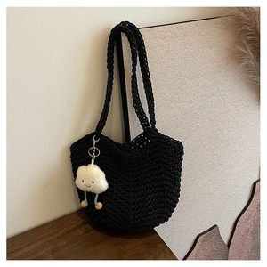 Detailed macro view of black crochet shoulder bag with white cloud plush pendant