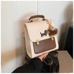 Detail of vintage beige and brown backpack featuring dachshund embroidery and plush charm