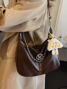 Brown pleated crescent bag with silver chain and cute mushroom pendant on shoulder