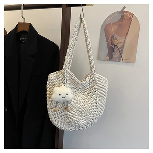 Detail of hollow woven cream tote bag with cute plush cloud pendant on wooden hanger