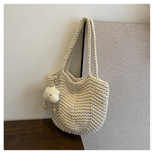 Detail of hand-woven cream tote bag with cute cloud plush charm and crochet texture