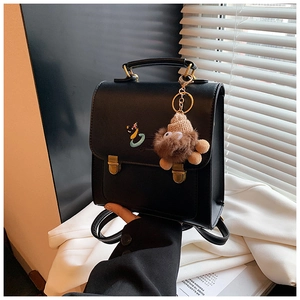 Detail of black leather backpack featuring gold buckles and a cute plush charm