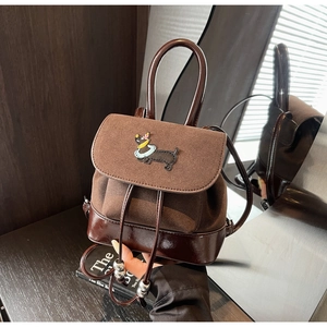 Detail eines dunkelbraunen Mini-Rucksacks aus Wildleder und Lackleder mit Dackel-Stickerei