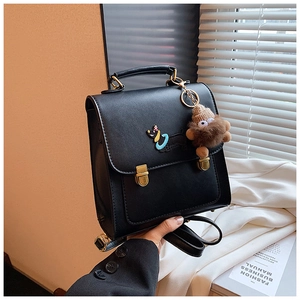Detail of black PU leather backpack with gold lock, dog embroidery and plush charm