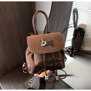 Detail eines braunen Vintage-Rucksacks mit Dackel-Stickerei und Kordelzugverschluss