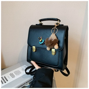 Close-up of black PU backpack featuring cat embroidery and brown plush keychain